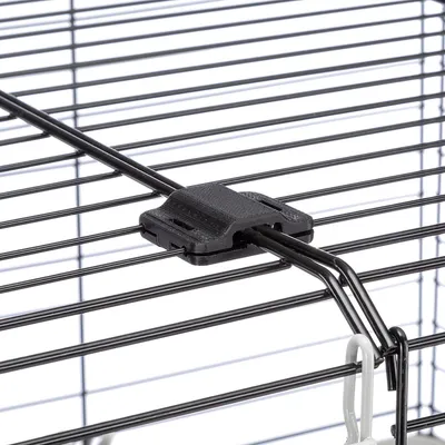 Détail d’une grille en métal noir avec fermeture en plastique noir, partie supérieure d’une cage pour animaux visible.