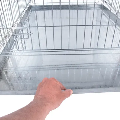 Mâna trage o tavă metalică detașabilă dintr-o cușcă cu pereți din grilaj.