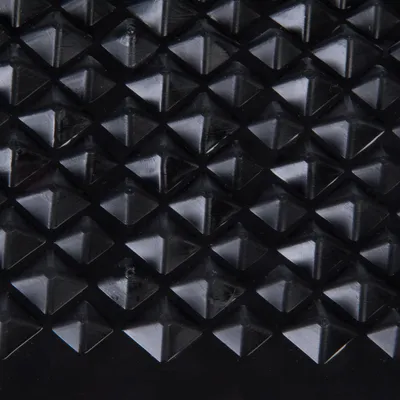 Detailný záber na čierny povrch s pyramídovými výstupkami, pravdepodobne štruktúra materiálu produktu.