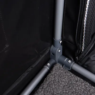 Detailaufnahme eines grauen Metallgestells mit schwarzem Stoff und Reissverschluss sowie einer grauen, strukturierten Bodenmatte.