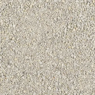 Detail světlého sypkého materiálu s drobnými kamínky a zrny různých velikostí, barva šedobéžová. Materiál je zřetelně zrnitý.