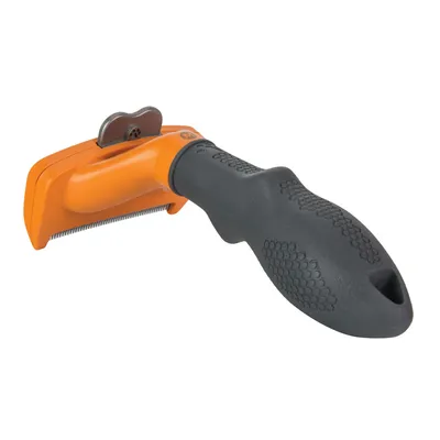 Cepillo para mascotas con mango negro antideslizante y cabezal naranja con púas metálicas visibles. Materiales: plástico y metal.