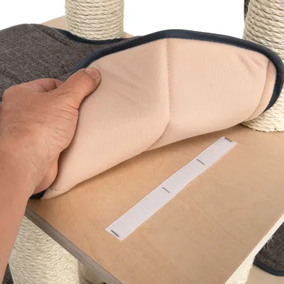Hand hebt ein gepolstertes Kissen mit Klettverschluss von einer Holzplattform, um die Befestigung zu zeigen.