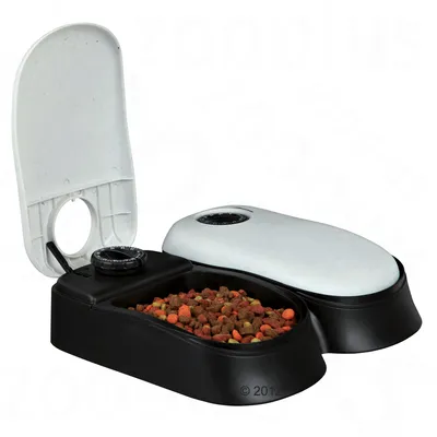 Автоматична хранилка с два отделения, едното отворено и пълно със суха храна, другото затворено. Черна основа, бели капаци с механичен таймер.