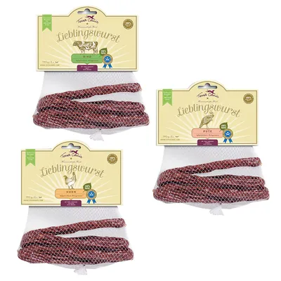 Три упаковки Terra Canis Lieblingswurst 190 г: Rind, Pute, Huhn. Колбаски в сетке, видны названия вкусов и изображения животных на этикетках.