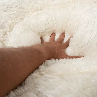 Hand pressing into soft, fluffy white material to demonstrate thickness and plush texture of the product surface.