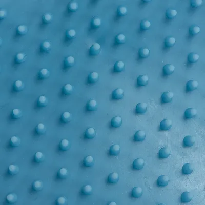 Nahaufnahme einer blauen Oberfläche mit gleichmässig verteilten Noppen, möglicherweise Materialstruktur eines Produkts.