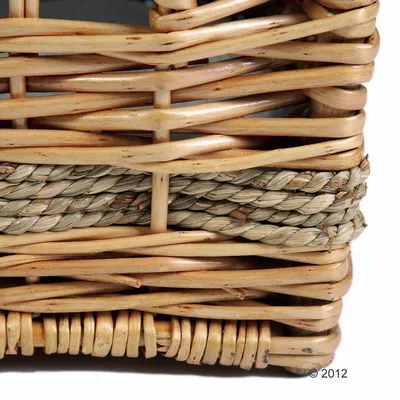 Detailopname van een mand van gevlochten natuurmateriaal, lichtbruin hout en grijs bastvlechtwerk.