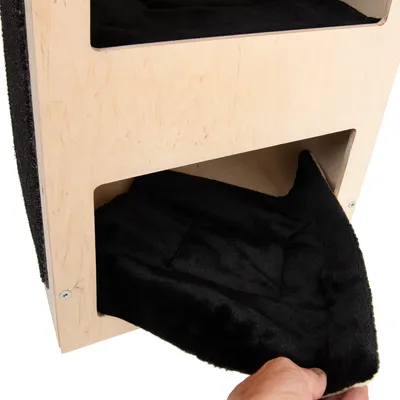 Vyjímatelný černý polštář z textilu v dolní přihrádce dřevěného boxu, detail ruky držící polštář.