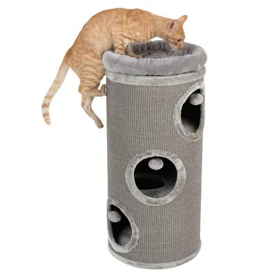 Grauer Kratzbaum in Zylinderform mit mehreren Öffnungen und Spielbällen. Eine orangefarbene Katze klettert oben auf den gepolsterten Rand.