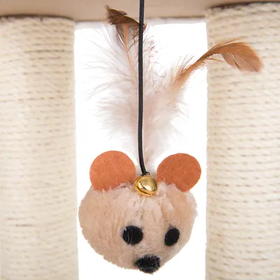 Jouet suspendu en forme de souris avec plumes, oreilles en feutrine, grelot doré et ficelle noire, accroché à un griffoir pour chat en sisal visible en arrière-plan.