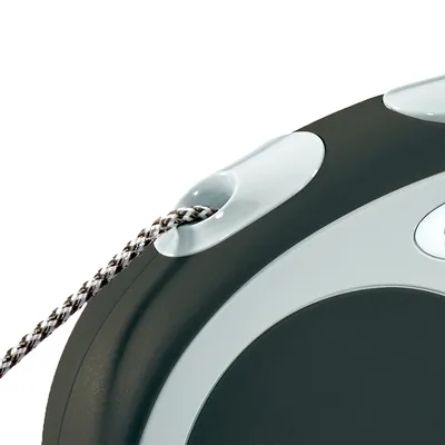 Dettaglio di guinzaglio avvolgibile con corda intrecciata bianca e nera, corpo in plastica grigia e bianca. Nessun testo visibile o marchio identificabile.