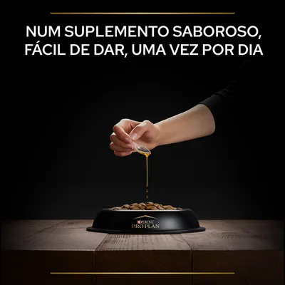 Texto: Num suplemento saboroso, fácil de dar, uma vez por dia. Mão a verter líquido sobre ração numa taça preta com marca Purina Pro Plan visível.