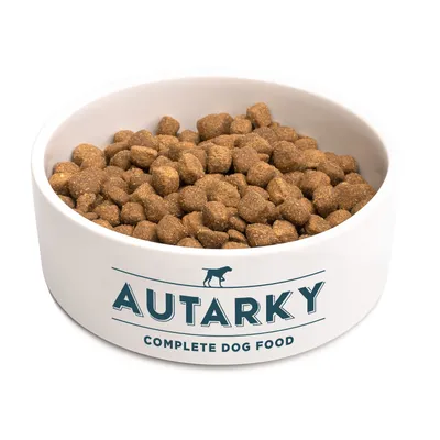 Bowl filled with Autarky complete dog food kibble, showing product name and type on the bowl.
