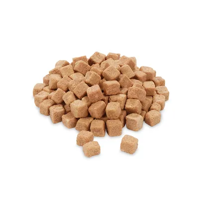 Karma w formie małych, brązowych kostek ułożonych w stos na białym tle. Widoczne pojedyncze kawałki, brak opakowania lub widocznych marek.
