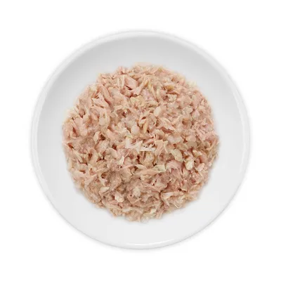 Wit bord met natvoer bestaande uit lichtroze, fijn gesneden stukjes vlees of vis. Geen merknaam of verpakking zichtbaar.