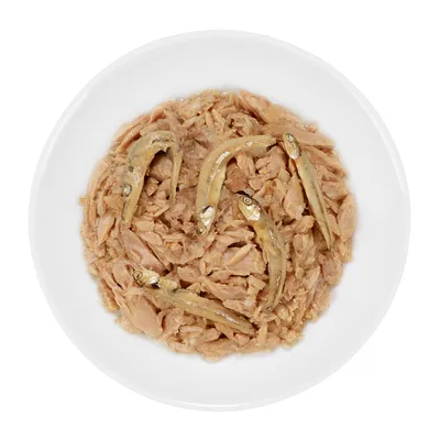 Schaal met natvoer bestaande uit stukjes vis en hele kleine vissen, zichtbaar op een witte achtergrond. Productinformatie zoals merk of ingrediënten niet zichtbaar.