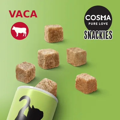 COSMA PURE LOVE SNACKIES, VACA. Cubos de snack saem de uma embalagem verde com silhueta de gato. Texto visível: 'VACA', 'COSMA PURE LOVE', 'SNACKIES'.