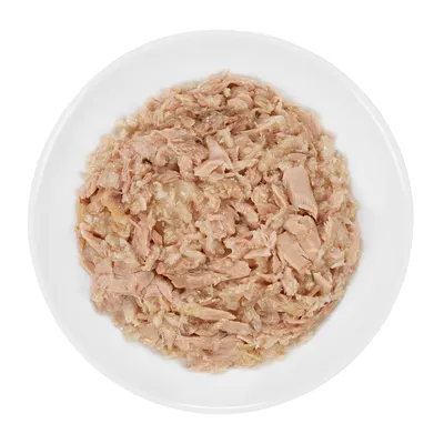 Assiette blanche contenant de la nourriture humide en morceaux, aspect effiloché, couleur beige rosé. Aucun emballage ni marque visible.
