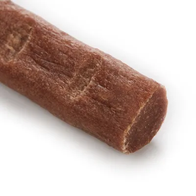 Nærbillede af en brun, cylindrisk hundesnack med glat tekstur og synlige indhak.
