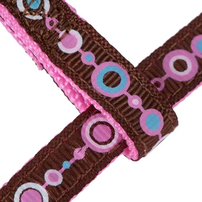 Primo piano di un nastro di stoffa marrone e rosa con motivo a cerchi colorati in blu, rosa e bianco.