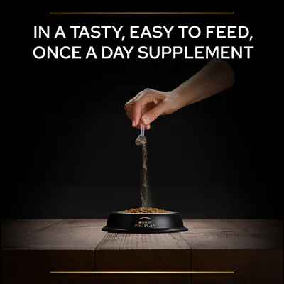 Hand sprinkling powder from a small scoop over kibble in a Purina Pro Plan bowl. Text: IN A TASTY, EASY TO FEED, ONCE A DAY SUPPLEMENT.