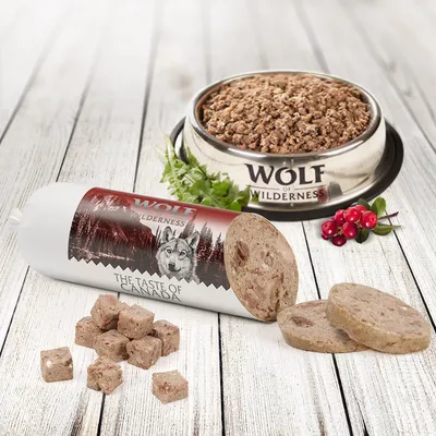 Wolf of Wilderness märkäruoka "The Taste of Canada" lihapaloilla, yrteillä ja karpaloilla. Ruokakuppi, tuote näkyvissä.