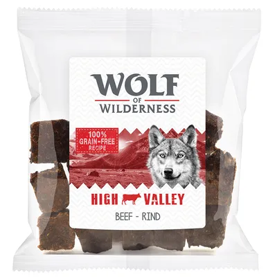 Упаковка лакомства Wolf of Wilderness High Valley Beef Rind, надпись: 100% grain-free recipe. Видны кусочки продукта внутри прозрачного пакета.