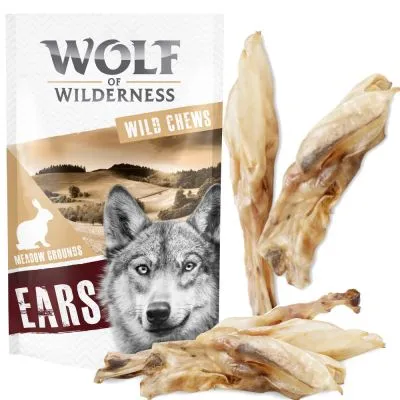 Wolf of Wilderness Wild Chews Meadow Grounds Ears – opakowanie oraz kilka suszonych uszu widocznych obok. Na opakowaniu sylwetka królika i krajobraz.