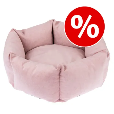 Rund lyserød hundeseng i stof med rød rabatmærke med hvidt procenttegn (%) synligt øverst til højre.