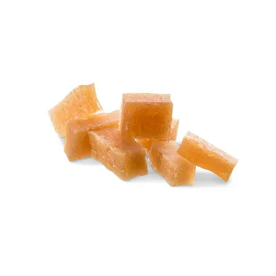 Morceaux de friandises en forme de cubes, couleur beige orangé, sans emballage ni marque visible, posés sur fond blanc.