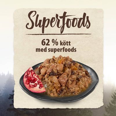 Tallrik med köttbaserad maträtt, text: Superfoods, 62 % kött med superfoods. Halv granatäpple synligt bredvid maten.