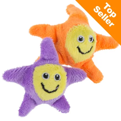 Två mjuka stjärnformade leksaker i lila och orange med glada ansikten. Text i hörnet: Top Seller.