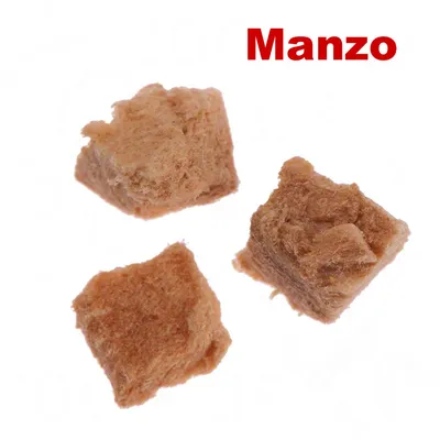 Tre cubetti di snack per animali, colore marrone chiaro, con la scritta visibile 'Manzo' in rosso in alto a destra.