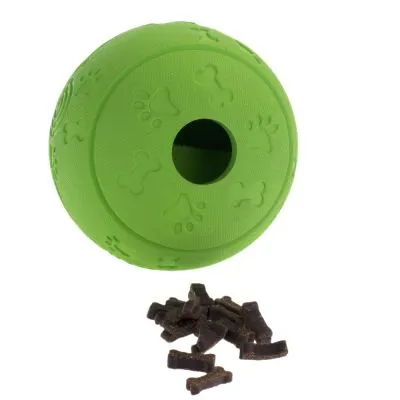 Palla verde in plastica con impronte di ossa e zampe, foro centrale visibile; accanto pezzi di snack marroni.