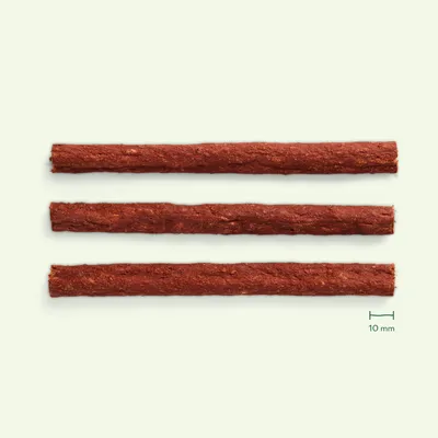 Trois bâtonnets d’aliment pour animaux, couleur brun rouge, disposés parallèlement. Repère de taille visible : 10 mm.