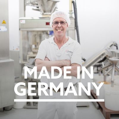 Made in Germany. Produktionsumgebung mit Maschinen und Mitarbeiter im weissen Arbeitsanzug, sichtbar ist der Schriftzug 'GimDog' auf dem Hemd.