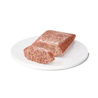 Närbild av en bit våtfoder, delvis uppskuren, presenterad på en vit tallrik.