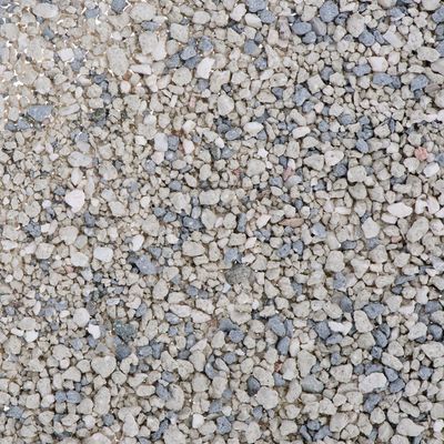 Nahaufnahme von grobkörnigem, grau-beigem Granulat mit unregelmäßigen Steinchen.