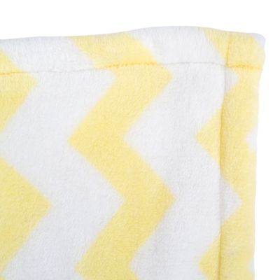 Крупный план желто-белого зигзагообразного узора на мягкой ткани.