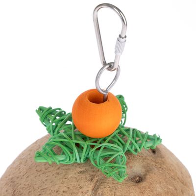 Jouet suspendu avec mousqueton en métal, boule orange en bois et étoile verte en rotin posées sur une surface marron.