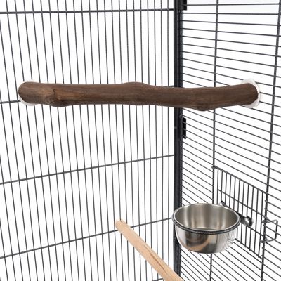 Perchoir en bois naturel fixé dans une cage à oiseaux, gamelle en acier inoxydable accrochée aux barreaux et perchoir droit en bois clair visibles au premier plan.
