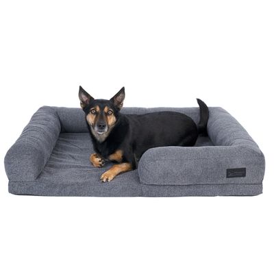 Chien noir allongé sur un grand panier rectangulaire gris en tissu avec rebords, étiquette visible portant la marque Modern Living.