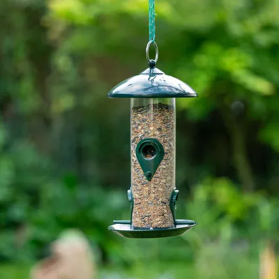 Hängender Vogelfutterspender aus Metall und Kunststoff, gefüllt mit Vogelfutter, geeignet für den Aussenbereich.