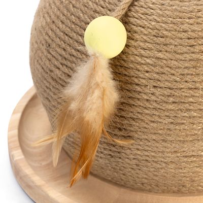 Leksak med gul boll och bruna fjädrar, fäst vid ett snöre av naturfiber på en träbas.