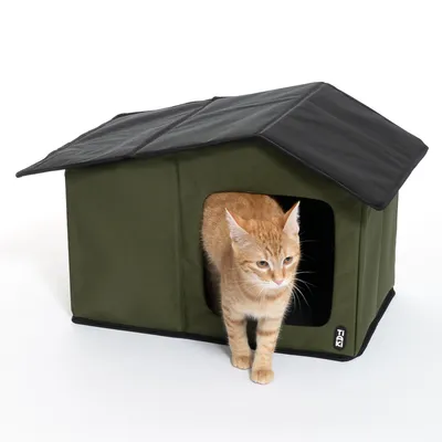 Casetta per animali verde con tetto nero, ingresso rettangolare e un animale arancione che esce. Logo del marchio 'Trixi' visibile in basso a destra.