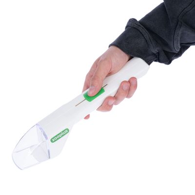 Kézben tartott fehér Zooplus etetőadagoló zöld csúszkával és átlátszó tartállyal.