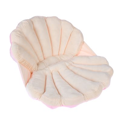 Cojín blando en forma de concha en beige y rosa con segmentos acolchados.