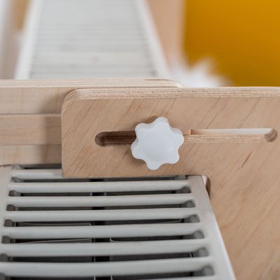 Close-up of a wooden slider with a white rotary knob, attached to a grid element. Shows the adjustment mechanism of the product.