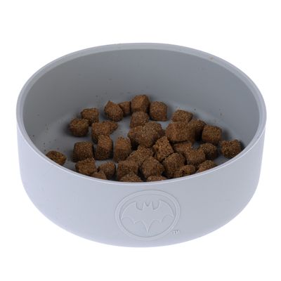 Ciotola grigia per alimenti con logo Batman, riempita con crocchette marroni.